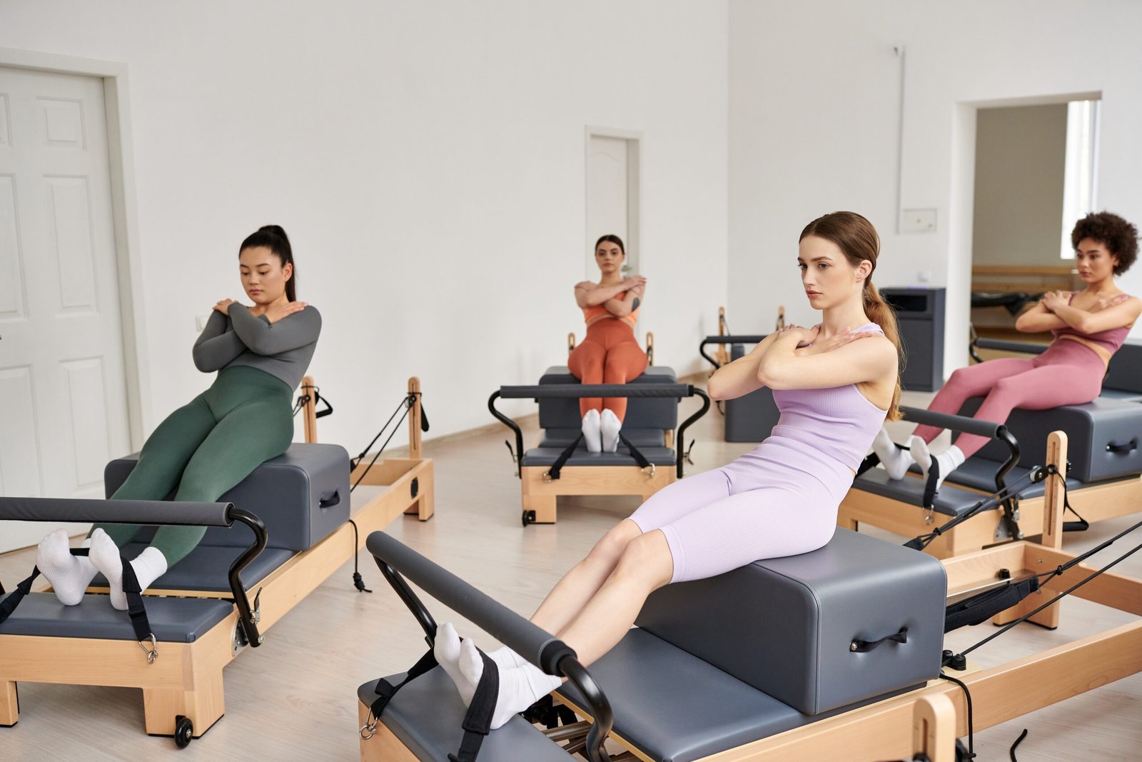 A vibrant group of pretty sporty women engaged in a Pilates lesson in a room.